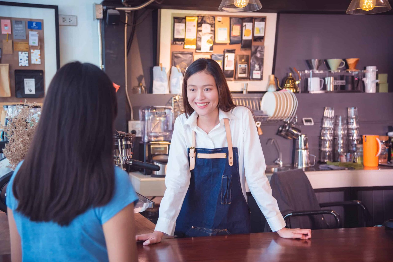 beautiful asian barista talking with her customer smiles her cafe scaled