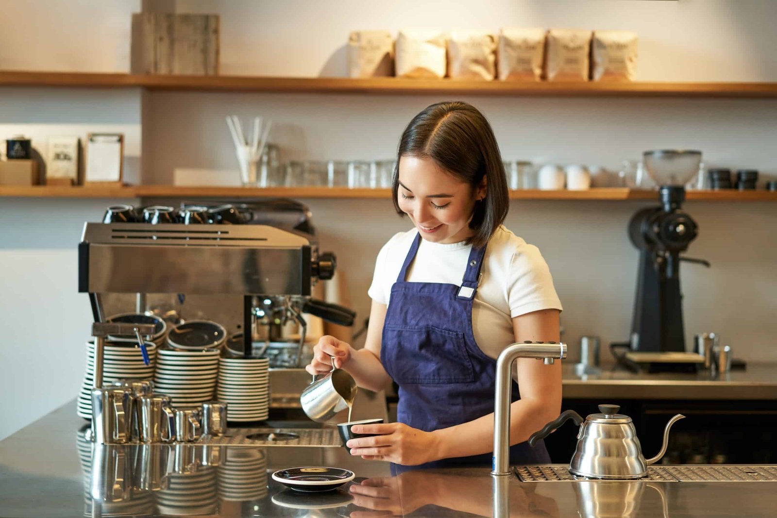 happy smiling cafe owner girl barista apron making cappuccino latte art with steamed milk standin scaled